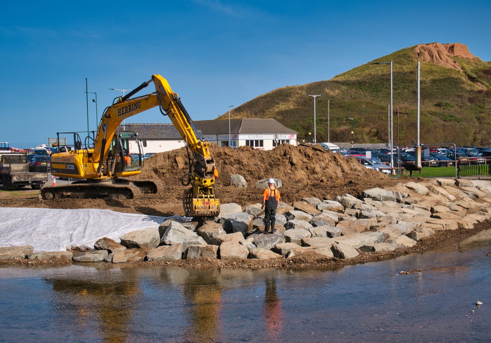 The construction of flood defences along Skelton Beck using heavy earth moving equipment and large stone blocks